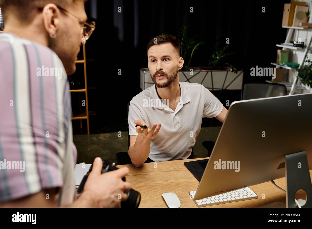 Due uomini si impegnano in una discussione a una scrivania in un ufficio. Foto Stock