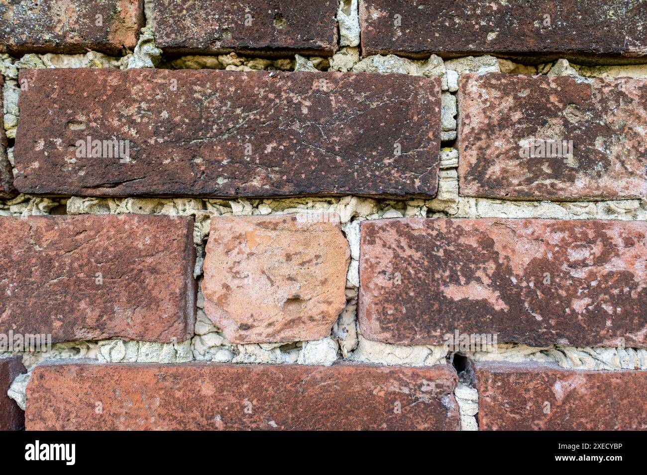 Un vecchio muro di mattoni intemprati che necessitava di essere riposizionato nel villaggio rurale britannico Foto Stock