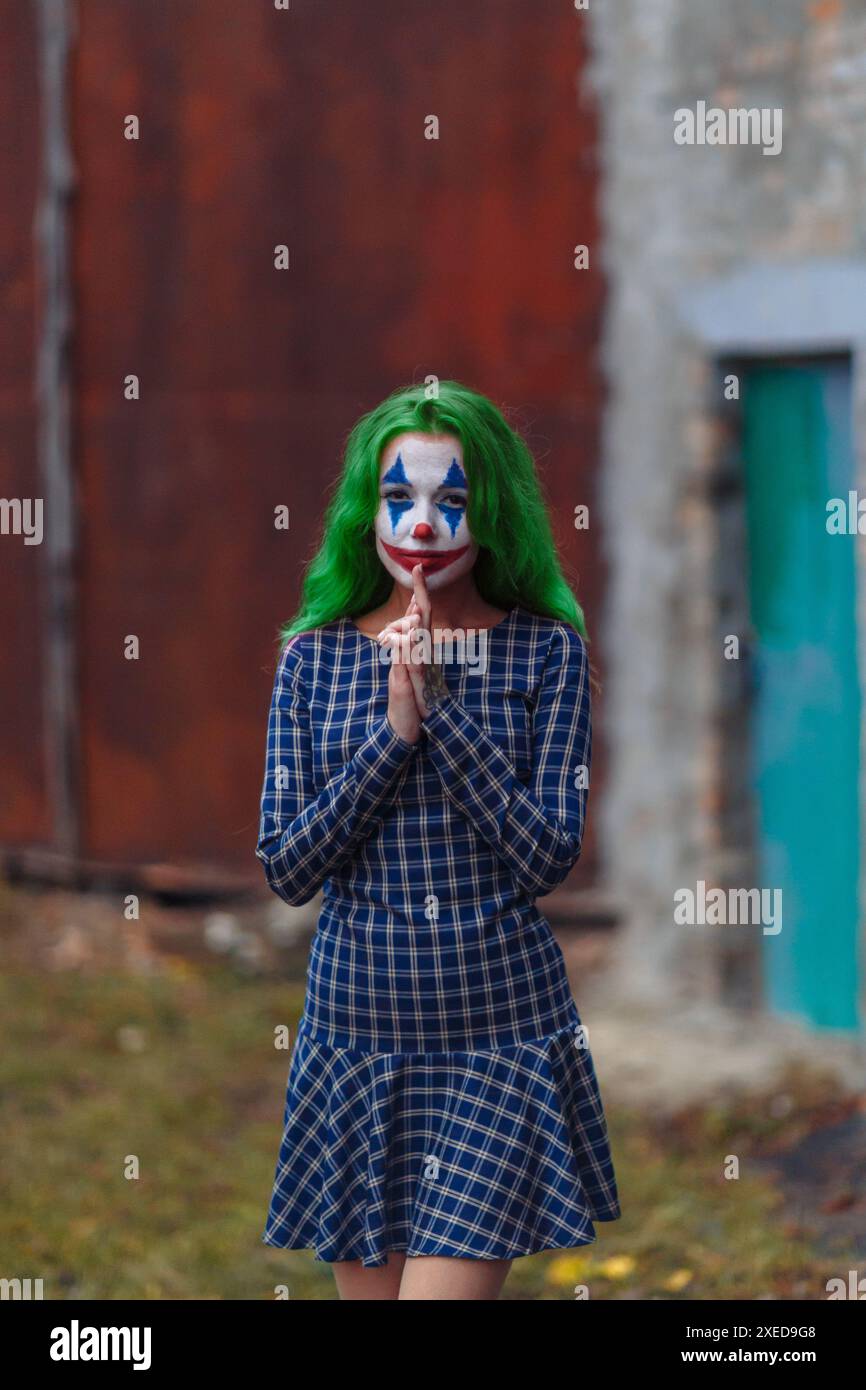 Ritratto di una ragazza con capelli verdi in abito da masticare con trucco joker su un ambiente atmosferico arrugginito parete di metallo. Foto Stock