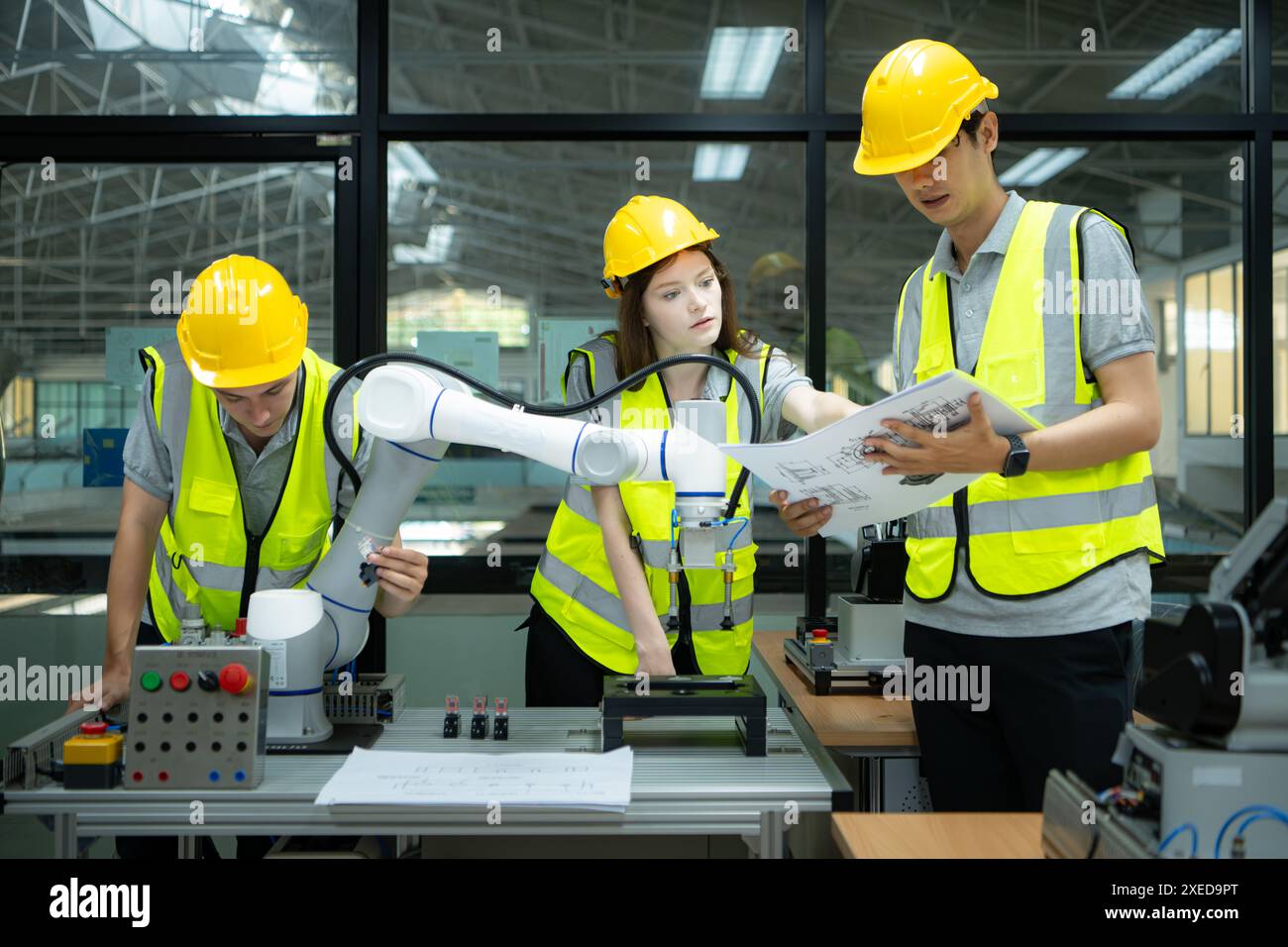 Gruppo di ingegneri e tecnici che apprendono la tecnologia per controllare i robot manuali per l'uso industriale. Foto Stock