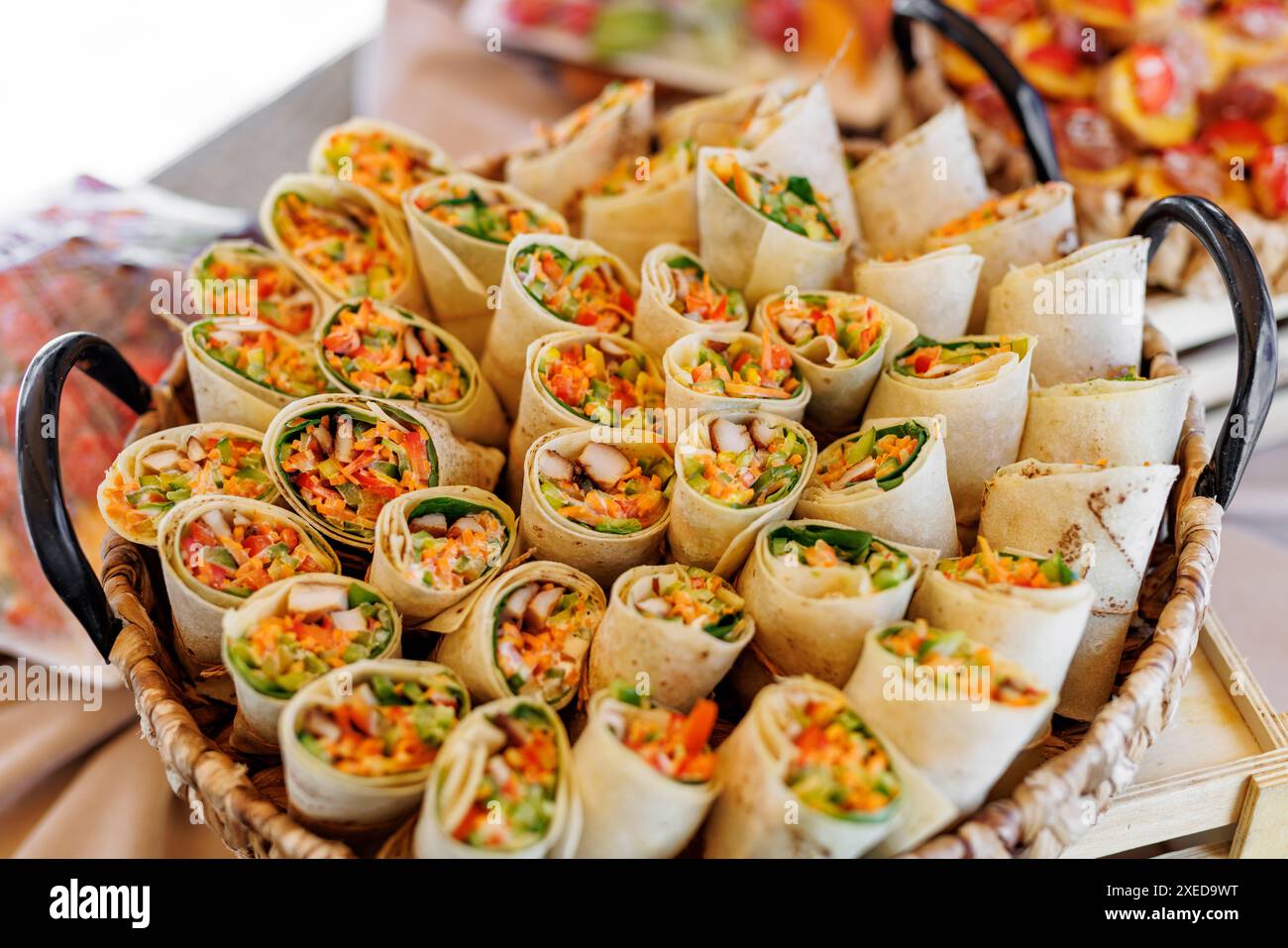 Involtini di verdure colorati e freschi disposti in un cestino di vimini. Foto Stock