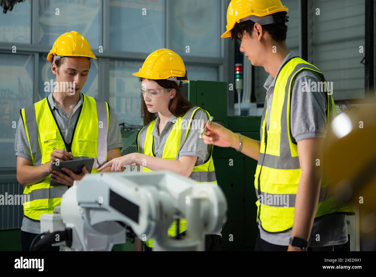 Ingegnere e tecnico che discutono del braccio robotico in fabbrica circa il funzionamento, la manutenzione e la riparazione del lavoro Foto Stock