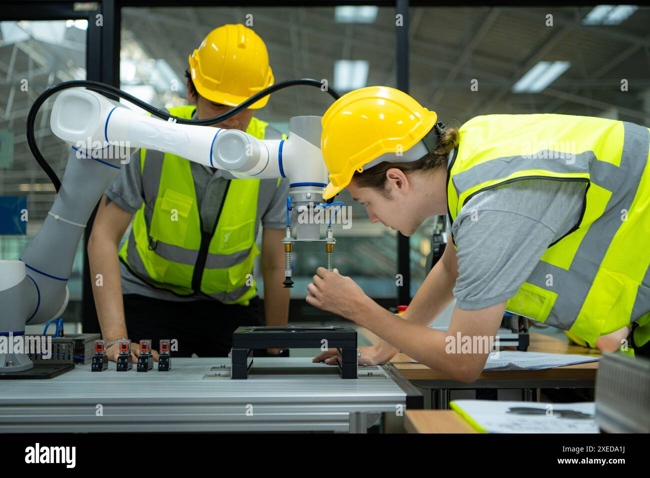 Gruppo di ingegneri e tecnici che apprendono la tecnologia per controllare i robot manuali per l'uso industriale. Foto Stock