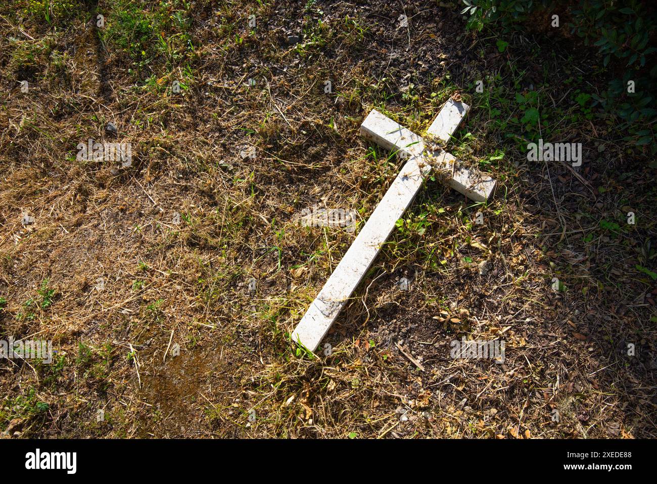 Crocifisso in cemento in pietra distrutta devastata a terra Foto Stock