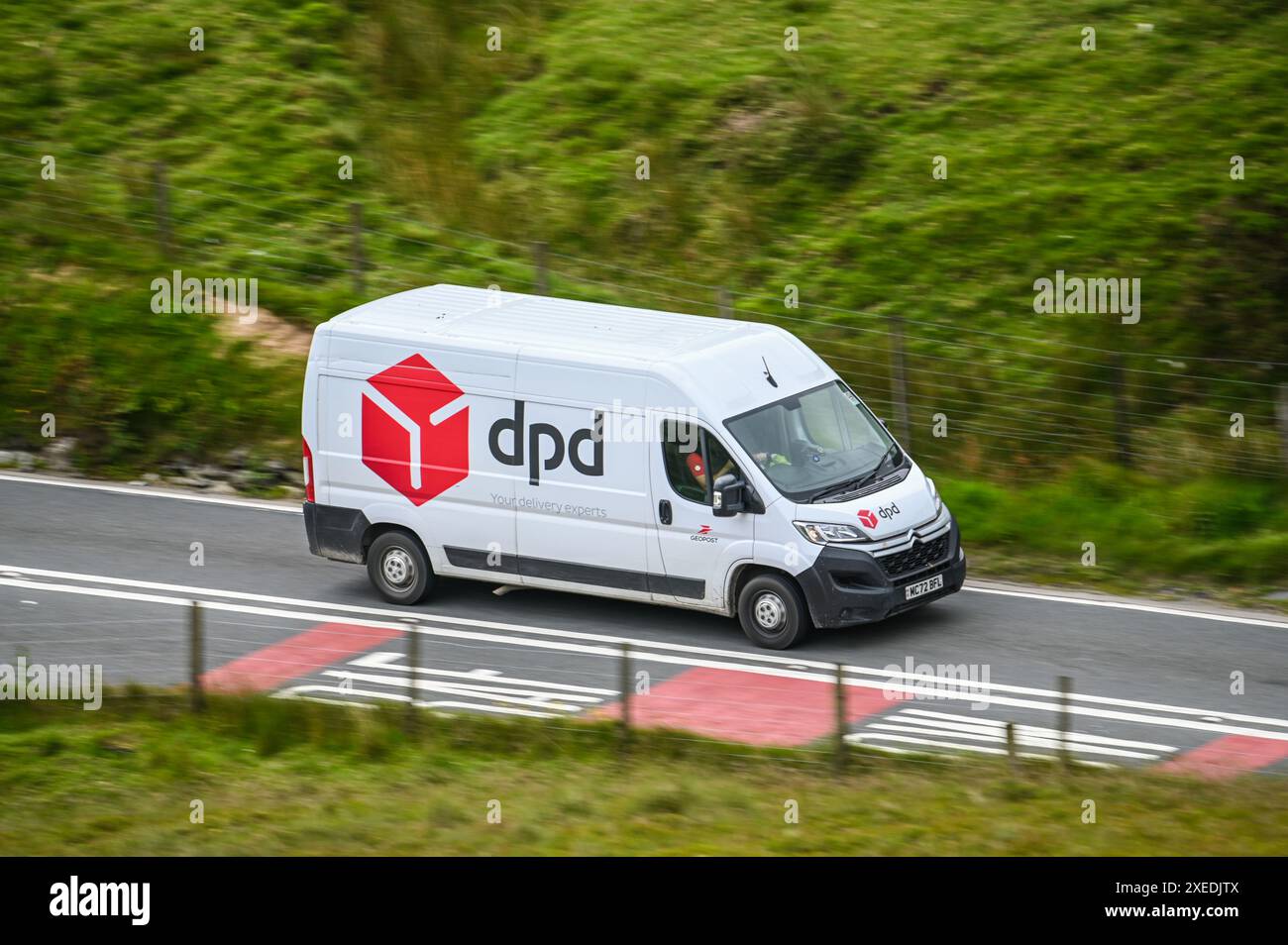 Furgone DPD Citroen Relay che alimenta lungo una strada gallese, consegnando pacchi in tutto il Galles centrale.r Foto Stock