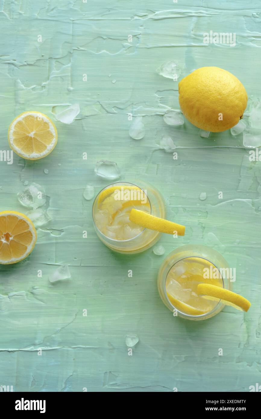 Limonata. Bere acqua di limone con ghiaccio, due bicchieri e frutta su blu Foto Stock