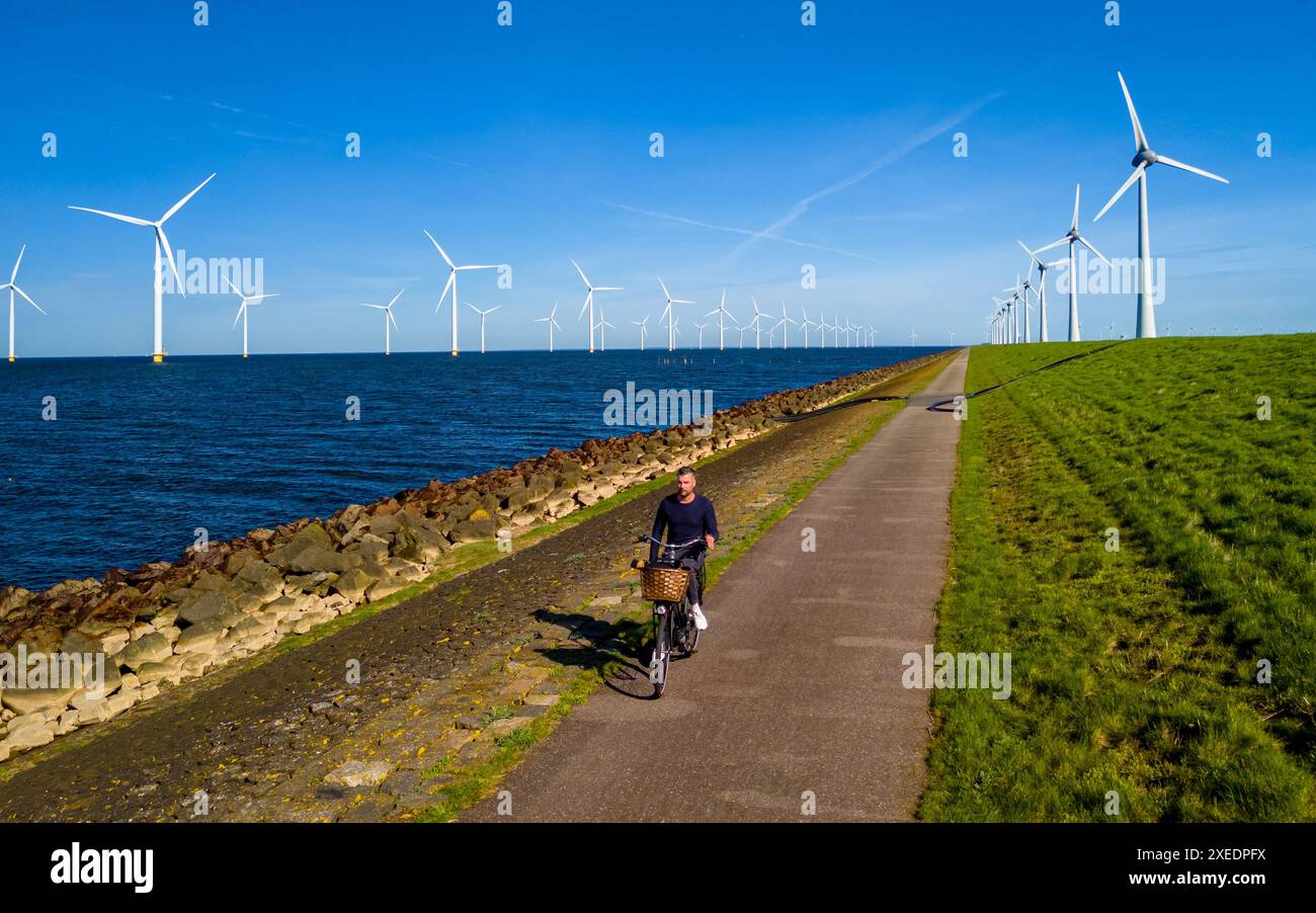 Un uomo sta pedalando lungo un sentiero tranquillo vicino al lago ijsselmeer n Flevoland, Paesi Bassi. Foto Stock