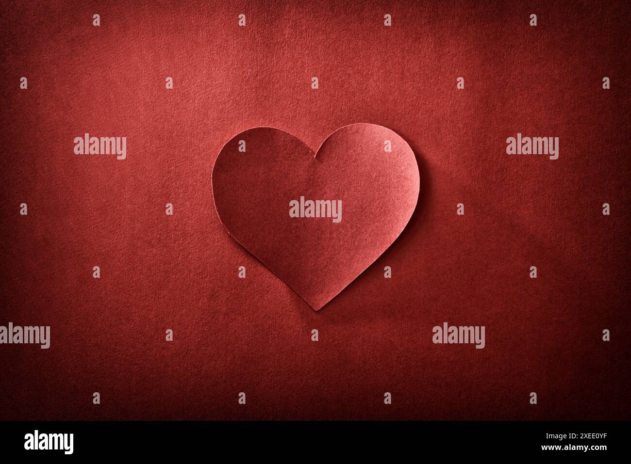 Ritaglio retro del cuore al centro isolato su sfondo rosso con texture e sfumatura. Vista dall'alto. Foto Stock