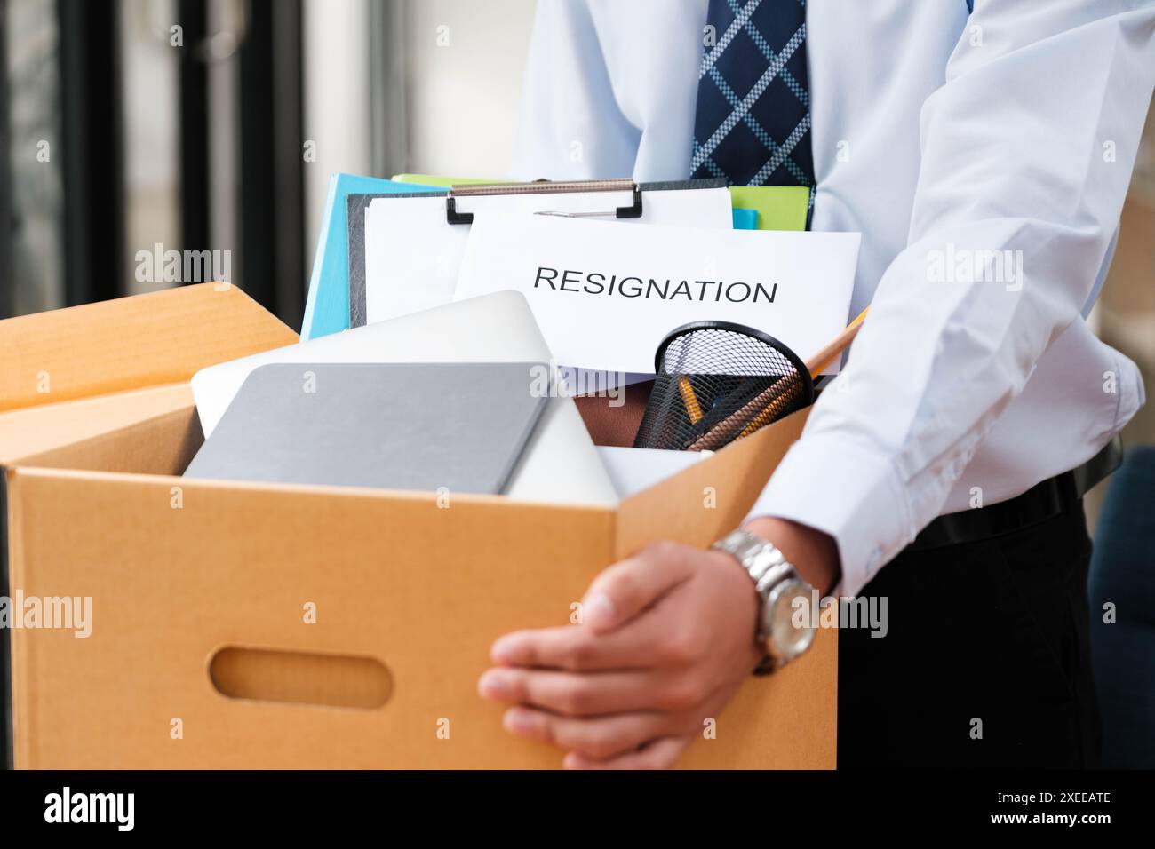 L'uomo mette oggetti personali e lettere di dimissioni in una scatola, ponendo fine al suo mandato. Foto Stock L'uomo mette oggetti personali e lettere di dimissioni in una scatola, ponendo fine al suo mandato. Foto Stock