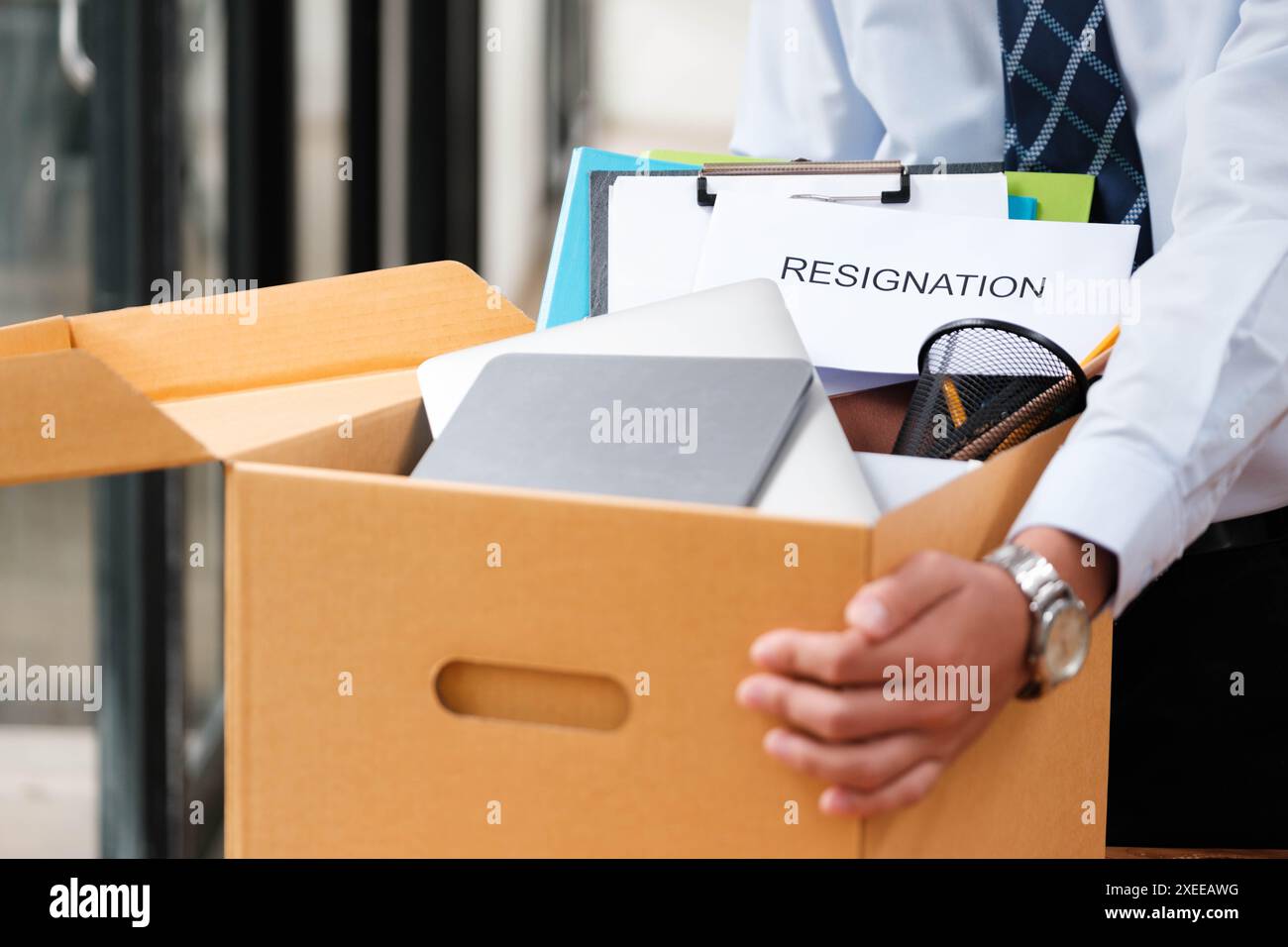 L'uomo mette oggetti personali e lettere di dimissioni in una scatola, ponendo fine al suo mandato. Foto Stock L'uomo mette oggetti personali e lettere di dimissioni in una scatola, ponendo fine al suo mandato. Foto Stock