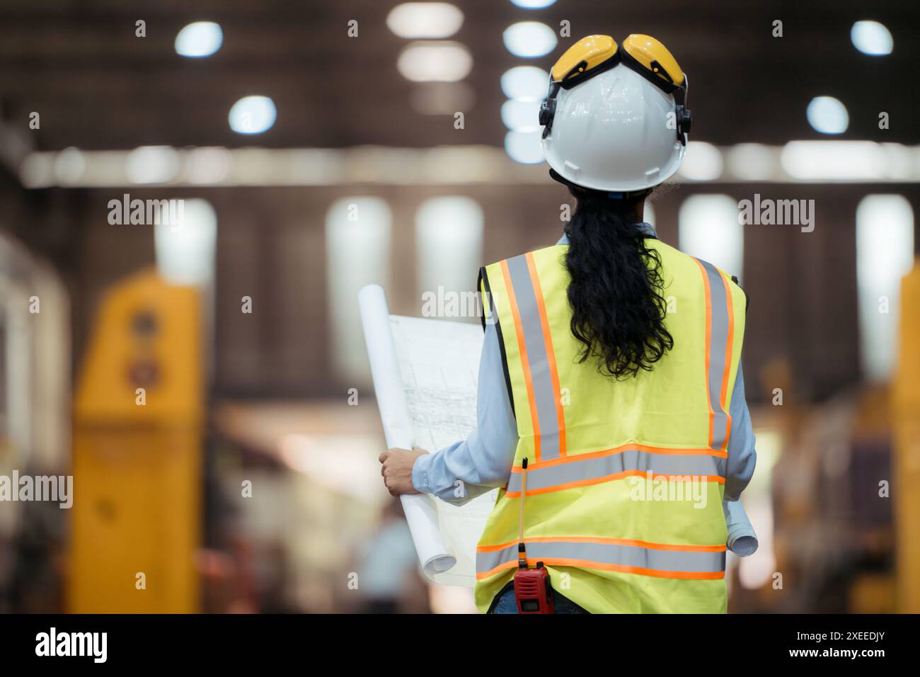 Ritratto del lavoratore tecnico ferroviario in giubbotto di sicurezza e casco che lavora con il progetto alla stazione di riparazione dei treni Foto Stock