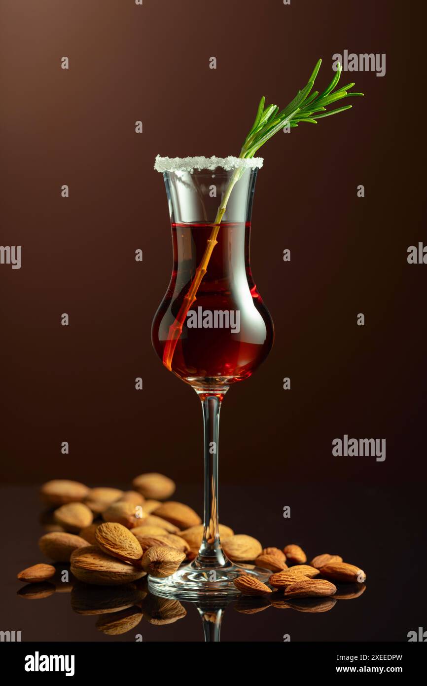 Liquore italiano alcolico forte Amaretto con noci di mandorle su fondo marrone. Foto Stock