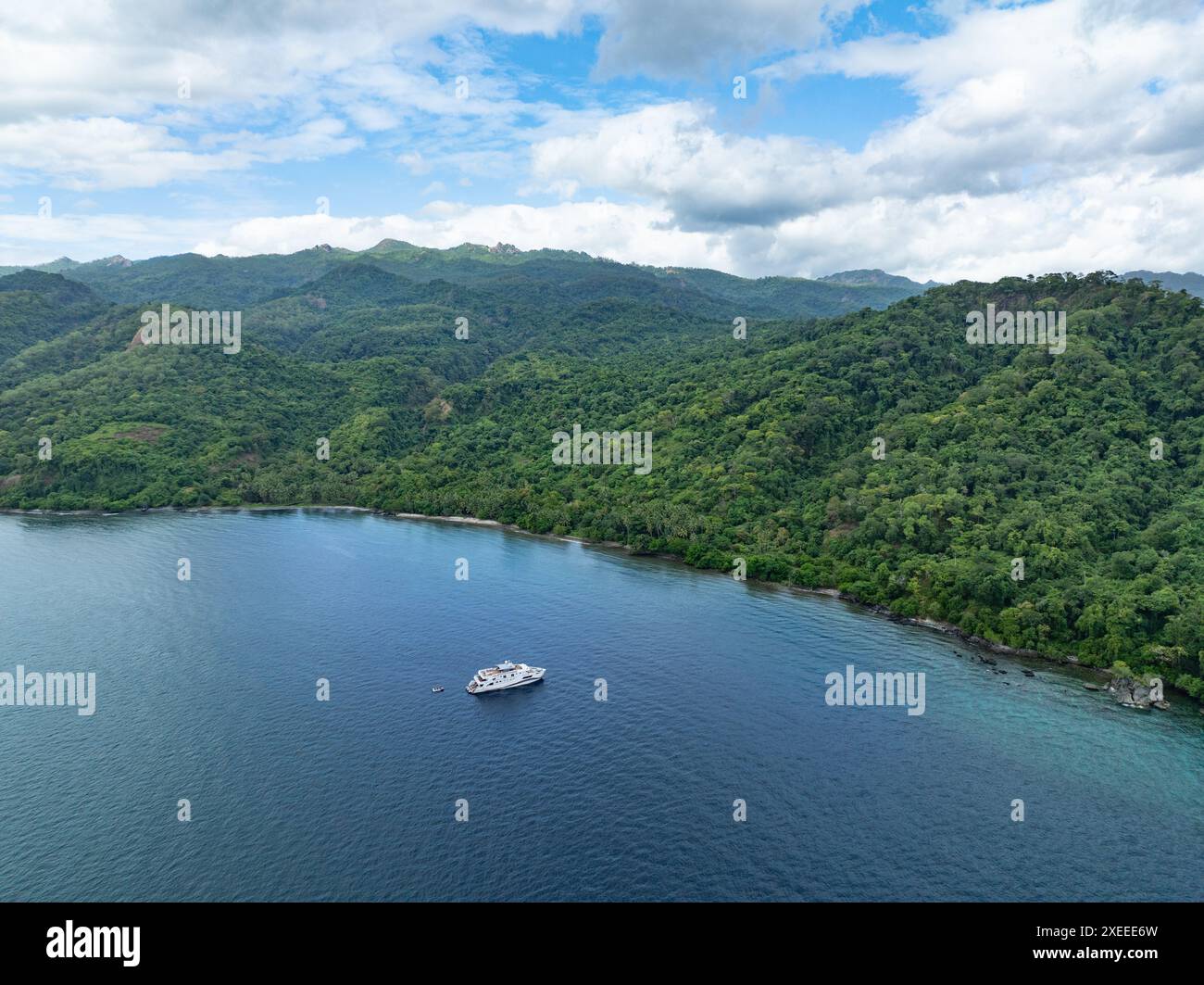 Una piccola barca subacquea si ferma all'ancora lungo la costa di una remota isola tropicale in Indonesia. Questa regione ospita una grande biodiversità marina. Foto Stock