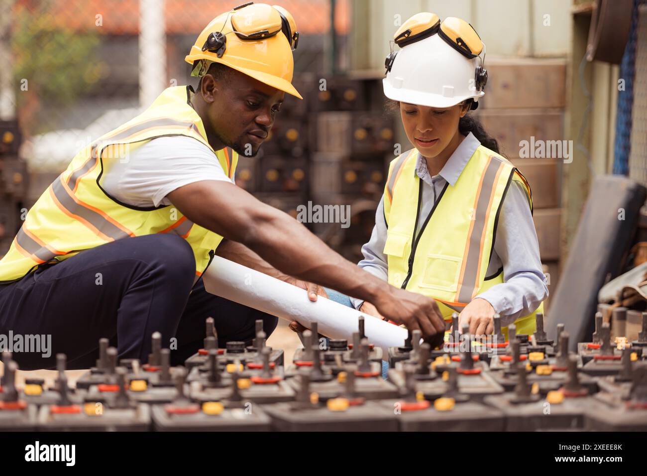 I tecnici ferroviari che lavorano con giubbotto di sicurezza e casco ispezionano la batteria nell'officina dei treni. Foto Stock