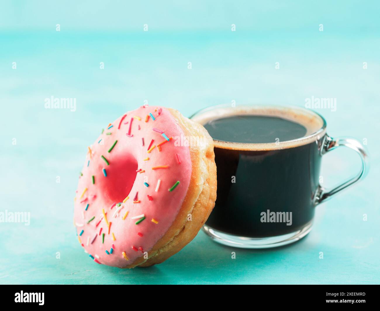 Ciambella rosa e caffè su sfondo blu , spazio copia Foto Stock