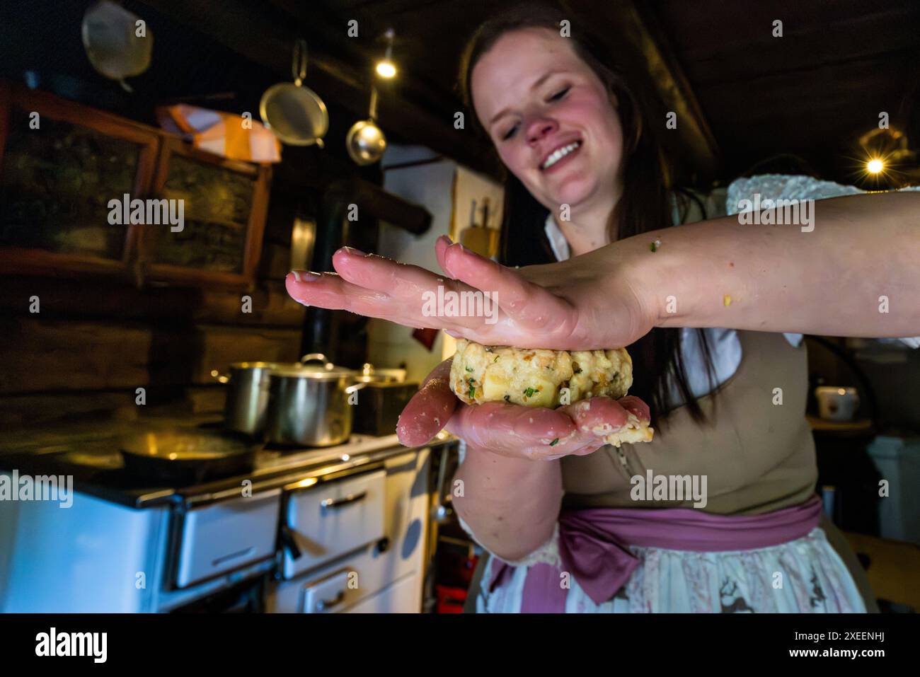 Il nome "Kaspressknödel" significa polpetta al formaggio in inglese e deriva dal pressare a mano la massa delle polpette fino a renderla piatta. L’oste e agricoltrice alpina Bettina Huber ne modella una alla Filzmoosalm nella valle di Großarl, Salisburgo, Austria. Foto Stock