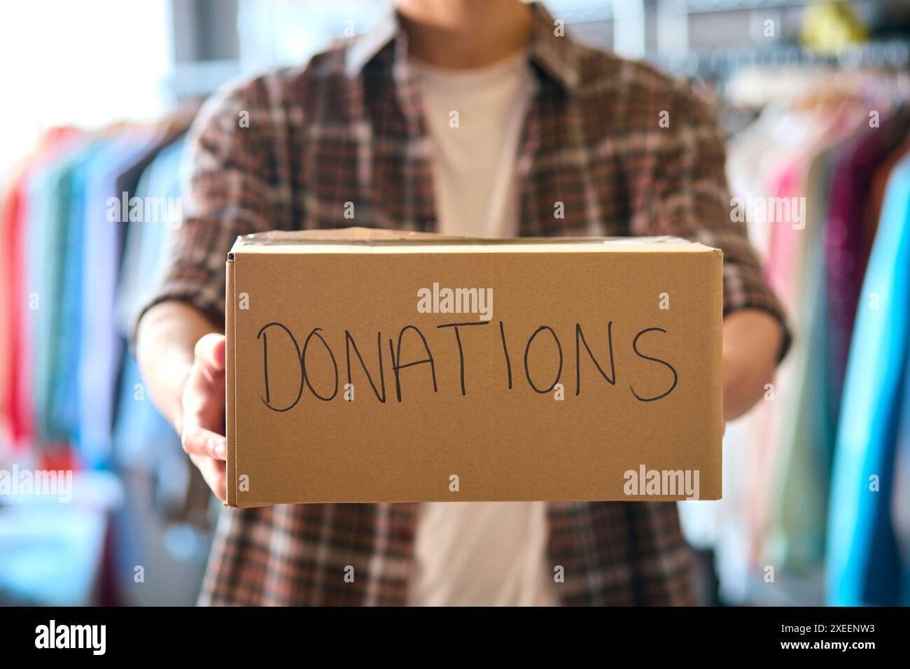 Primo piano di male Charity Volunteer che tiene in mano le donazioni etichettate Box verso la fotocamera Foto Stock