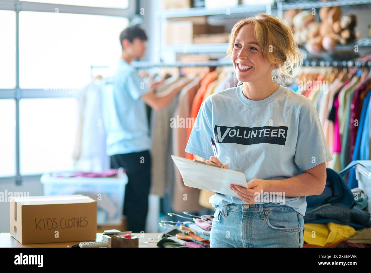 Lavoratrice di beneficenza che controlla le donazioni di abbigliamento al Thrift Store Foto Stock