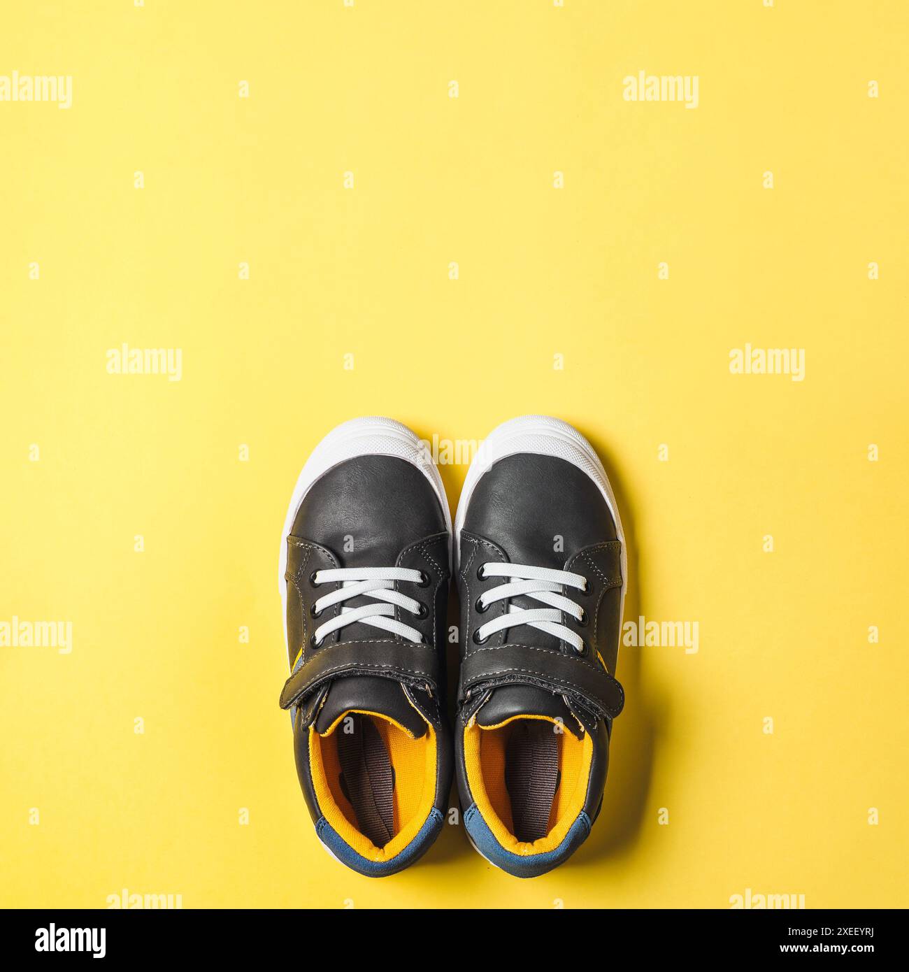 Sneaker grigie e gialle su sfondo giallo Foto Stock