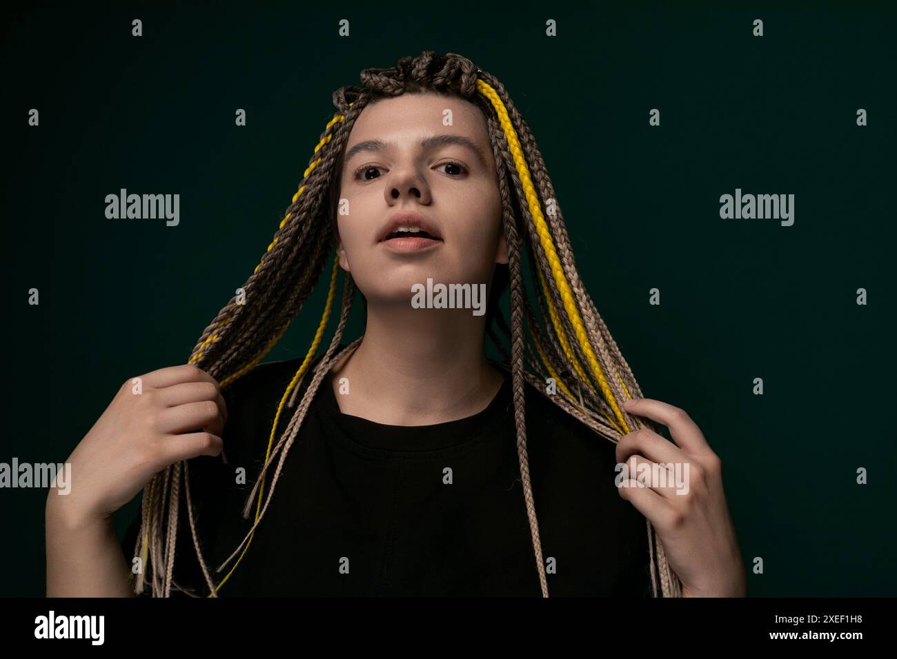 Donna con Dreadlock in piedi davanti allo sfondo verde Foto Stock