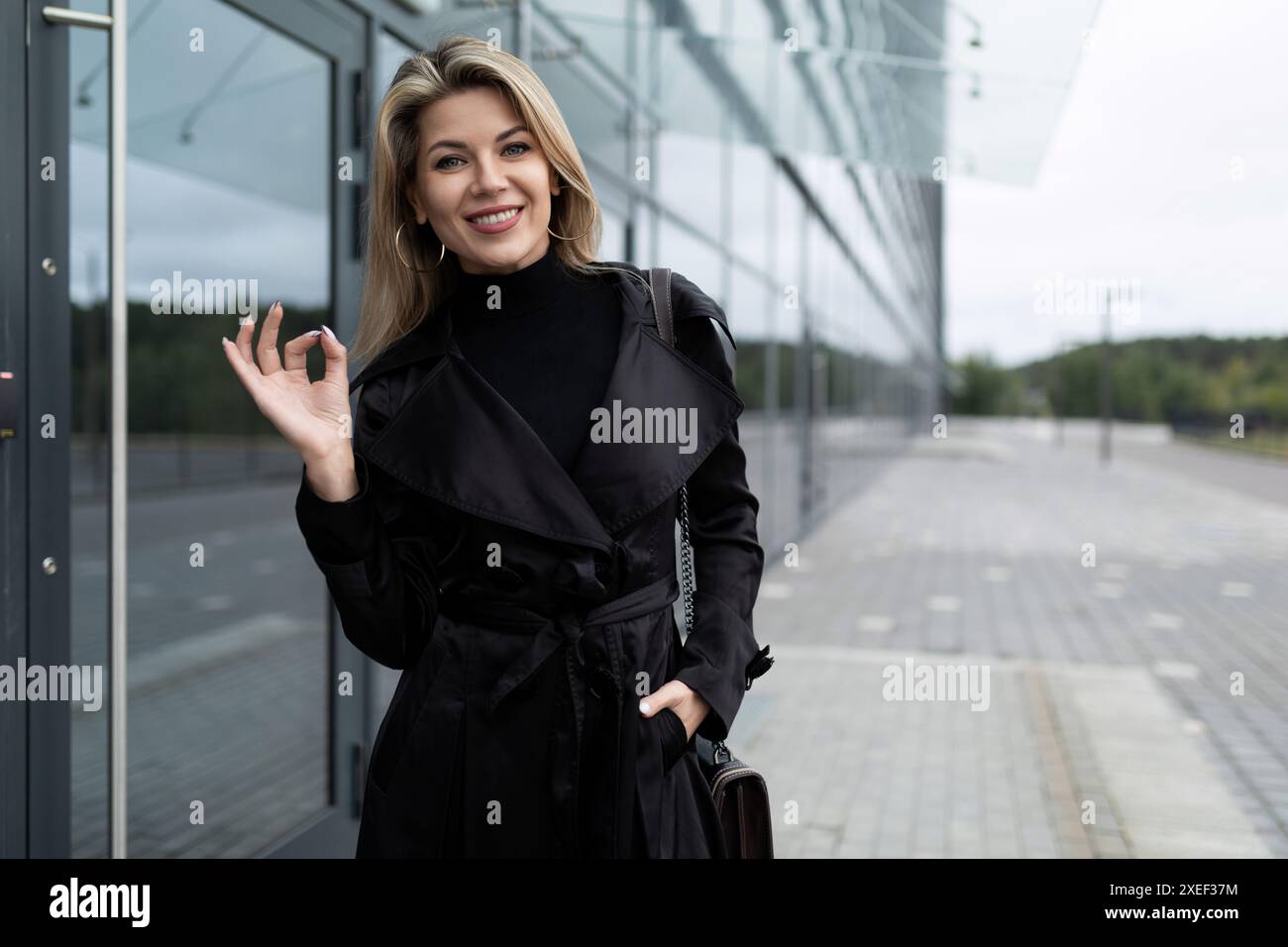 Una giovane investitore mostra un segno di fiducia con le mani sullo sfondo di un business center Foto Stock