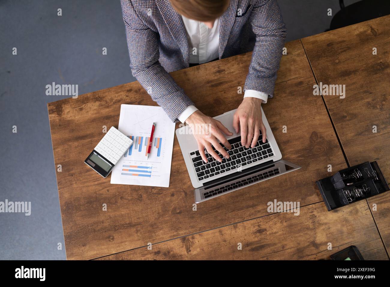 Uomo d'ufficio che lavora nel settore finanziario con grafici e laptop Foto Stock