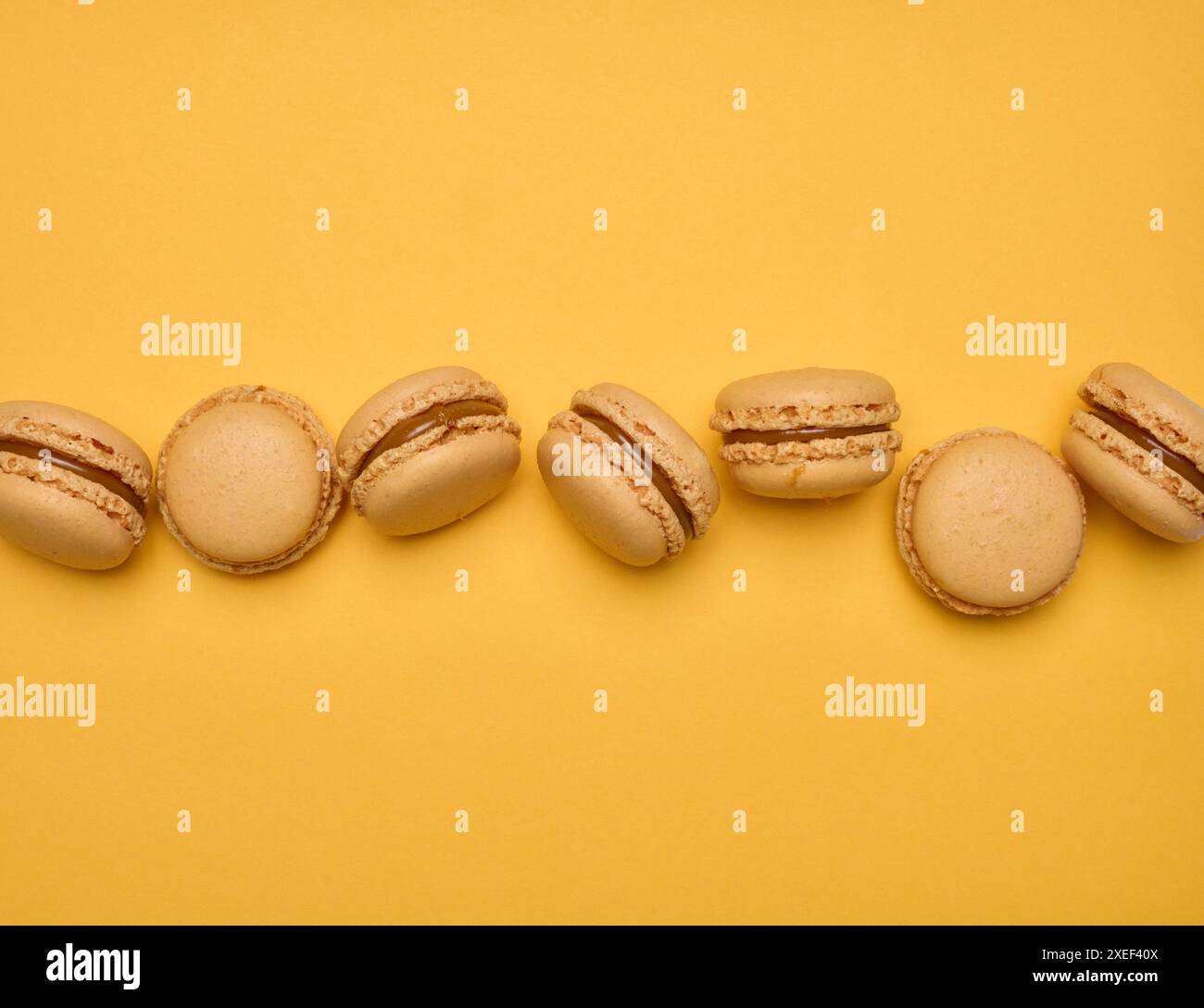 Macaron al cioccolato su sfondo giallo, dessert. Foto Stock