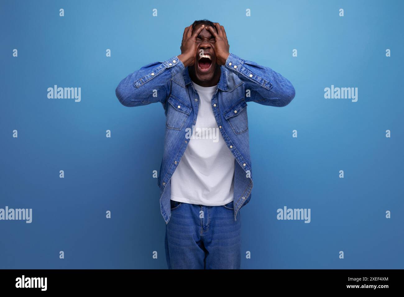 Scioccato uomo africano felice con dreadlocks in giacca di denim ha vinto la lotteria Foto Stock