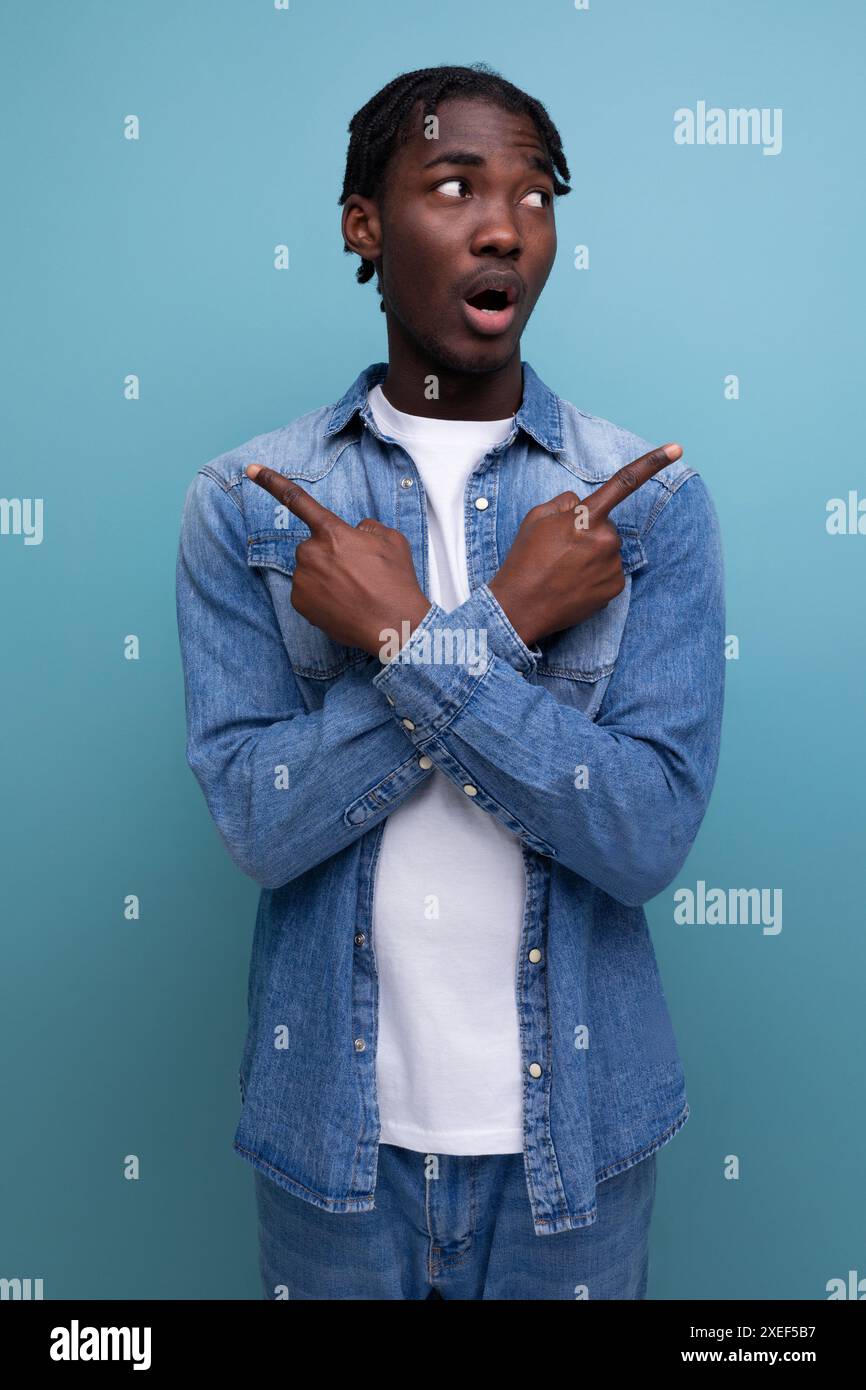 Felice e gioioso uomo africano con capelli ricci in un look casual sperimenta piacevoli emozioni Foto Stock