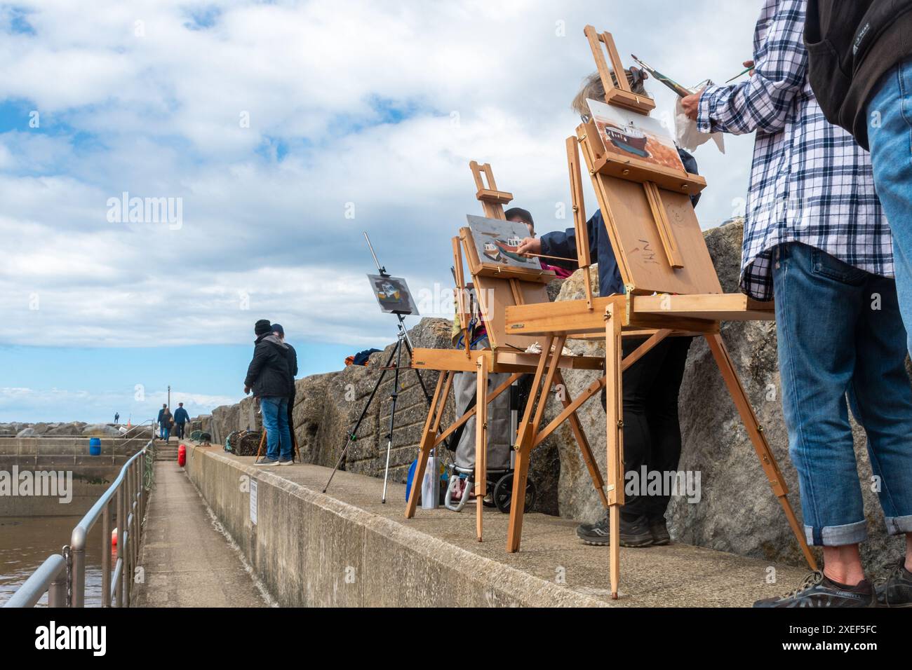 Artisti che dipingono all'aperto sul muro del porto di Staithes, un villaggio di pescatori nel North Yorkshire, Inghilterra, Regno Unito Foto Stock