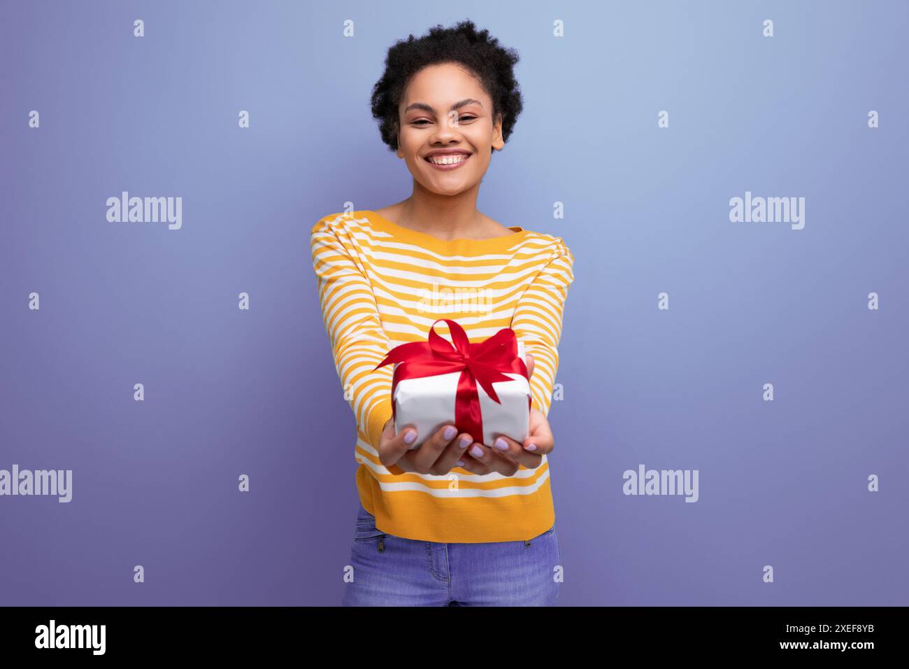 Felice afro bruna latina anni '20 giovane donna che regge fuori confezione regalo Foto Stock