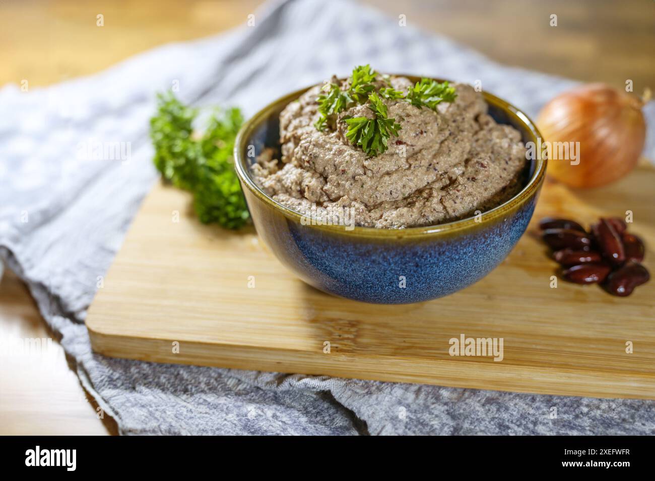 Salsa vegana a base vegetale che ricorda la salsiccia di fegato, fatta in casa con fagioli renali, tofu, cipolla ed erbe aromatiche, servita in una ciotola con guarnigioni di prezzemolo Foto Stock