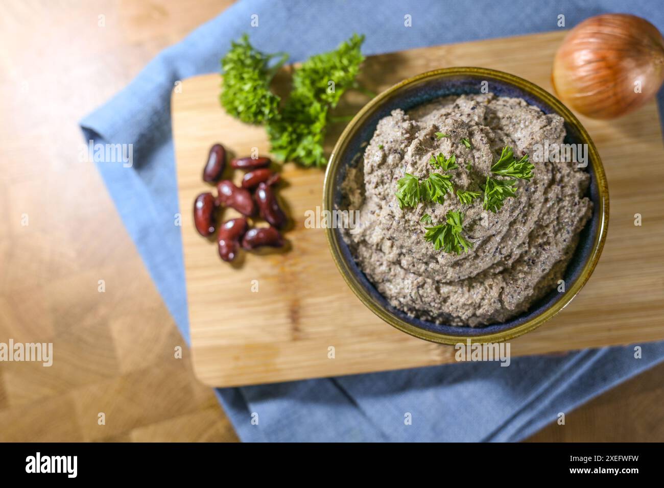 Alternativa vegetale per salsicce di fegato, salsa vegana fatta in casa da fagioli renali e tofu, servita in una ciotola con guarnigione di prezzemolo su un tavolo da cucina, da a. Foto Stock