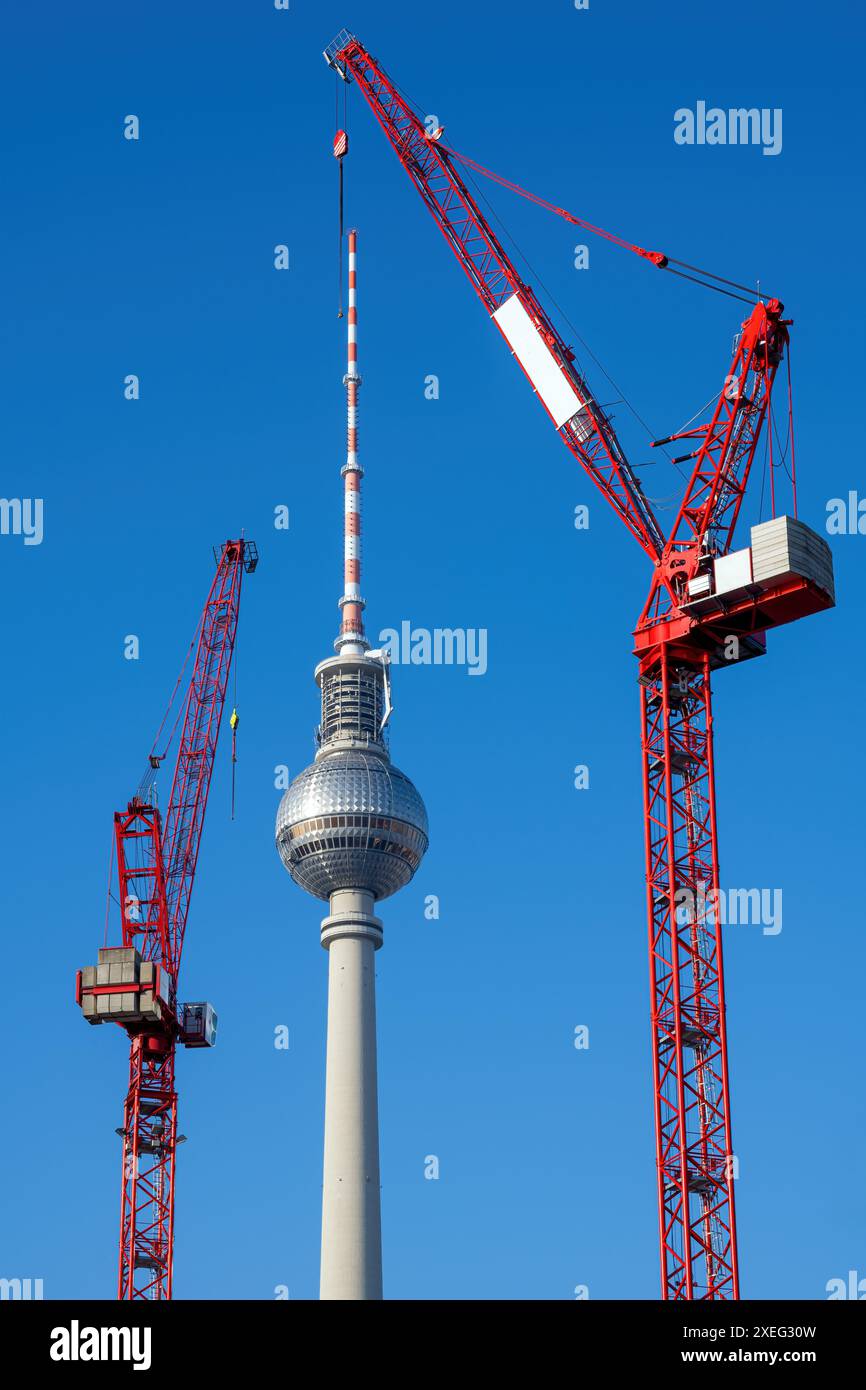 La famosa torre della televisione di Berlino con due gru a torre rosse Foto Stock