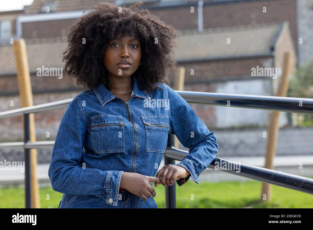 Giovane donna sicura di sé con un outfit casual in denim che si appoggia alla ringhiera Foto Stock