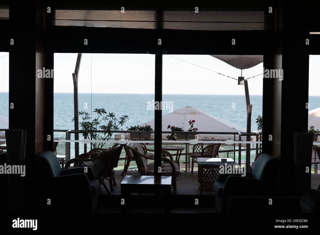 L'interno vuoto della caffetteria si affaccia su una spiaggia tranquilla con mare calmo, offrendo un ambiente tranquillo e invitante Foto Stock