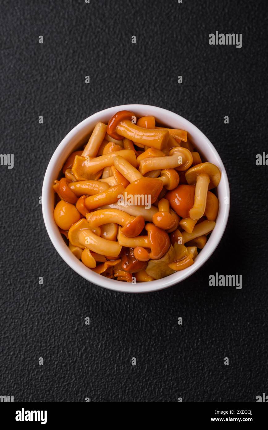 Deliziosi funghi al miele sottaceto con sale e spezie in un piatto di ceramica Foto Stock