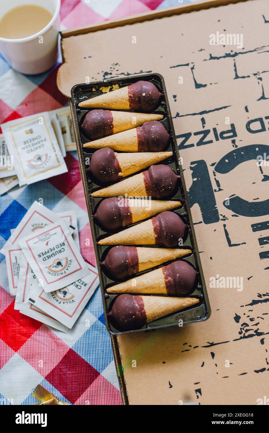 mini coni di gelato alla vaniglia ricoperti di cioccolato in confezione durante la festa della pizza Foto Stock