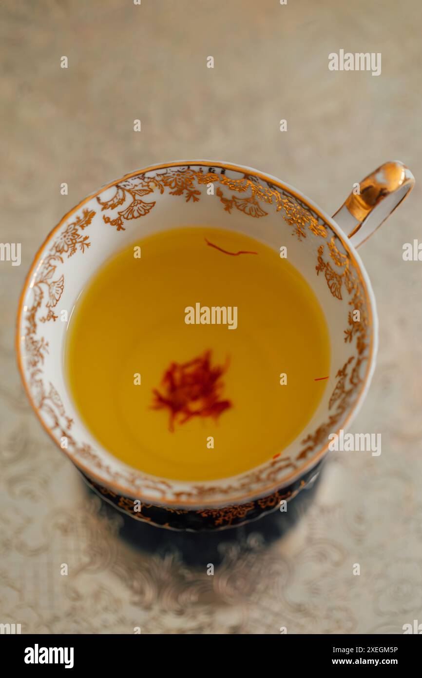 tè allo zafferano giallo con fili rossi in oro ornato e tè bianco su vassoio d'argento Foto Stock