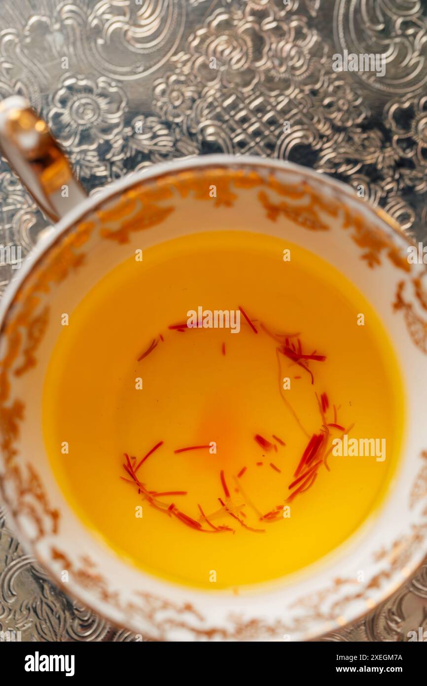 tè allo zafferano giallo con fili rossi in oro ornato e tè bianco su vassoio d'argento Foto Stock