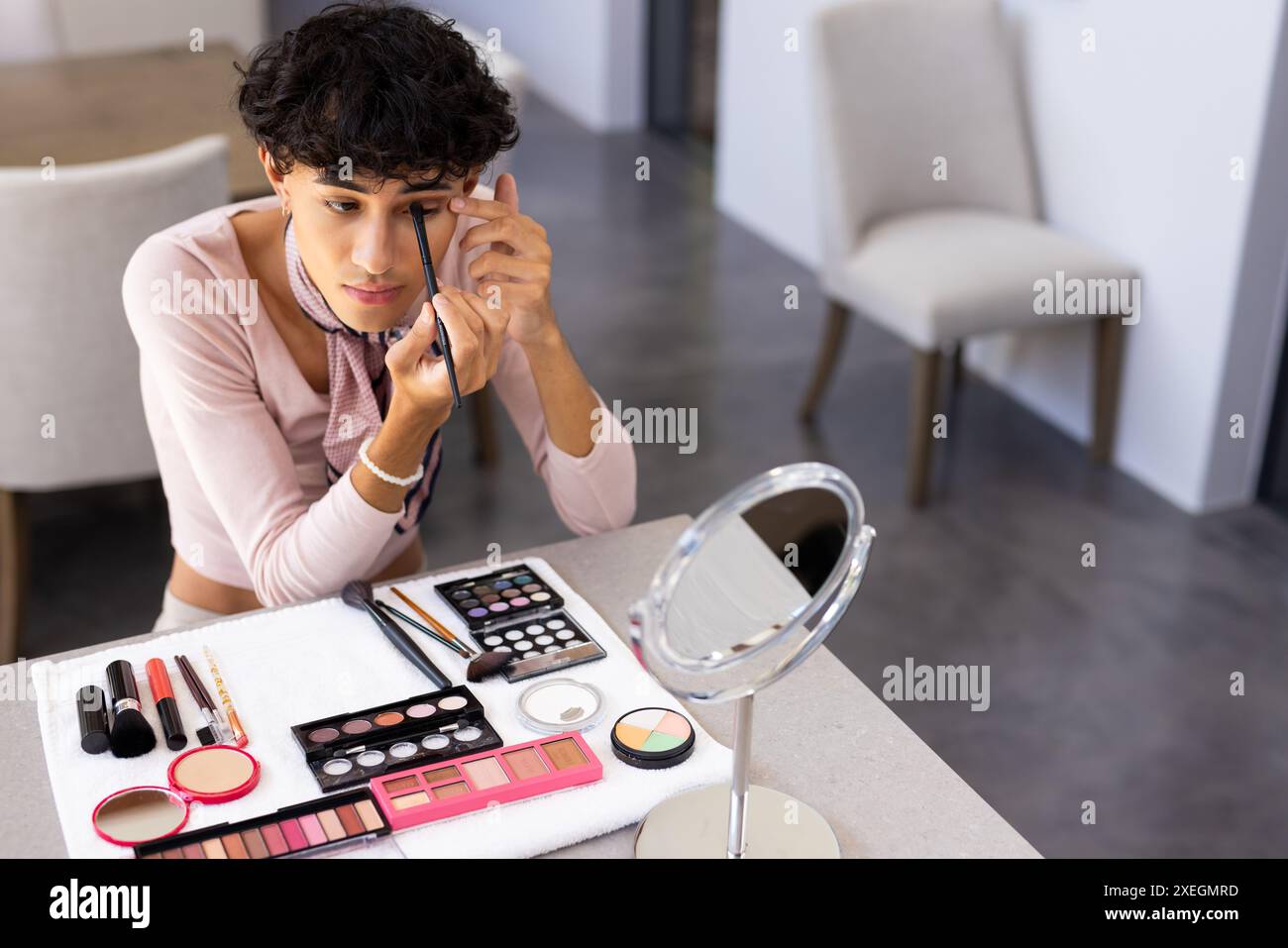 Applicazione dell'eyeliner, donna transgender che utilizza strumenti di trucco al tavolo da bagno Foto Stock