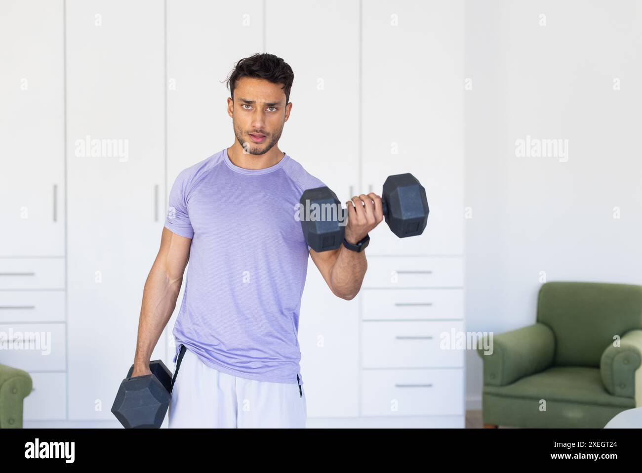 Manubri per il sollevamento, uomo che si allena a casa per il fitness e l'allenamento di forza Foto Stock