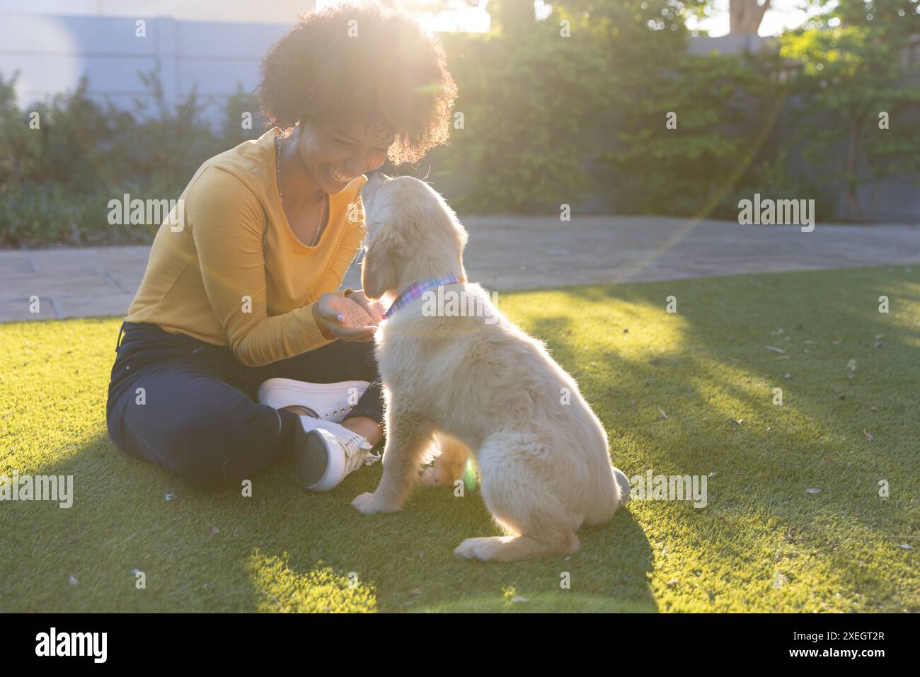 Giocare con il cane in cortile, donna che si gode una giornata di sole e si lega con il cucciolo Foto Stock