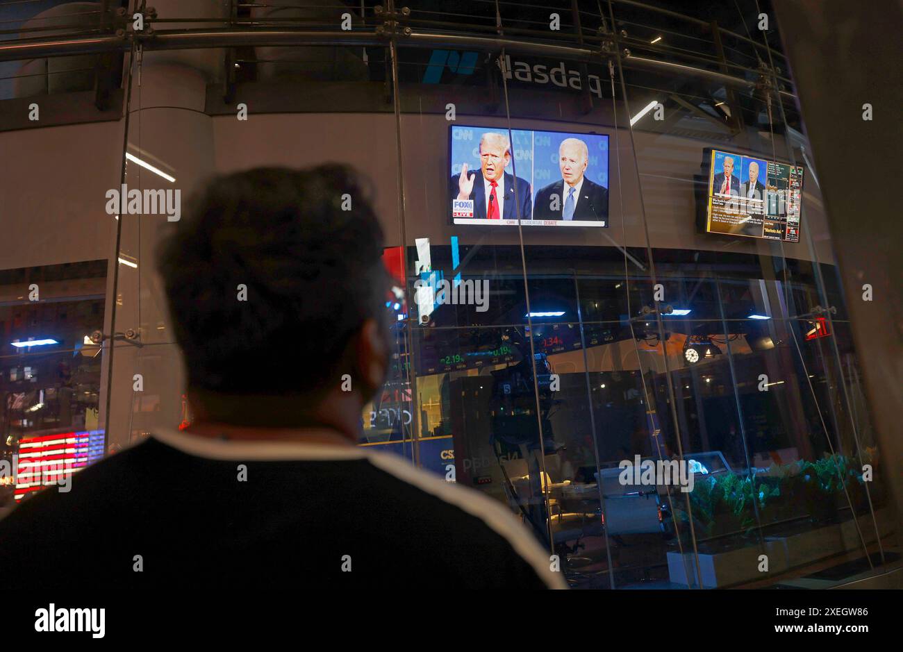 New York, Stati Uniti. 27 giugno 2024. Un visitatore di Times Square guarda i monitor televisivi che mostrano il dibattito presidenziale della CNN tra il presidente Joe Biden e l'ex presidente Donald Trump a New York giovedì 27 giugno 2024. Il dibattito si svolge negli studi di Atlanta della CNN con Jake Tapper e Dana Bash come moderatori. Foto di John Angelillo/UPI credito: UPI/Alamy Live News Foto Stock