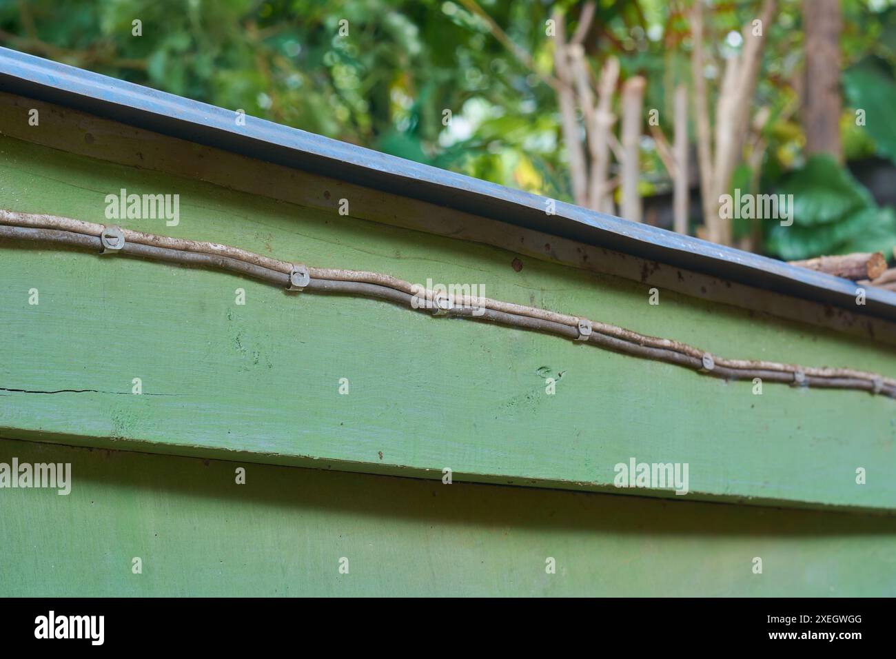 vecchi fili elettrici fissati alla superficie in legno con clip metalliche, scorrono lungo la vecchia struttura in legno per esterni, messa a fuoco selettiva con spazio di copia Foto Stock