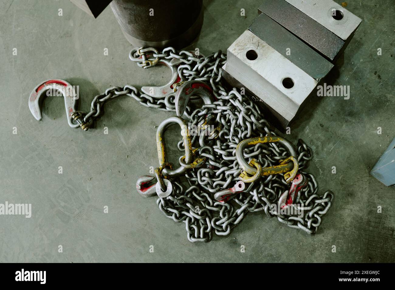 Parte superiore-inferiore di catene con ganci su pavimento grigio, parte di attrezzature di sollevamento industriali Foto Stock