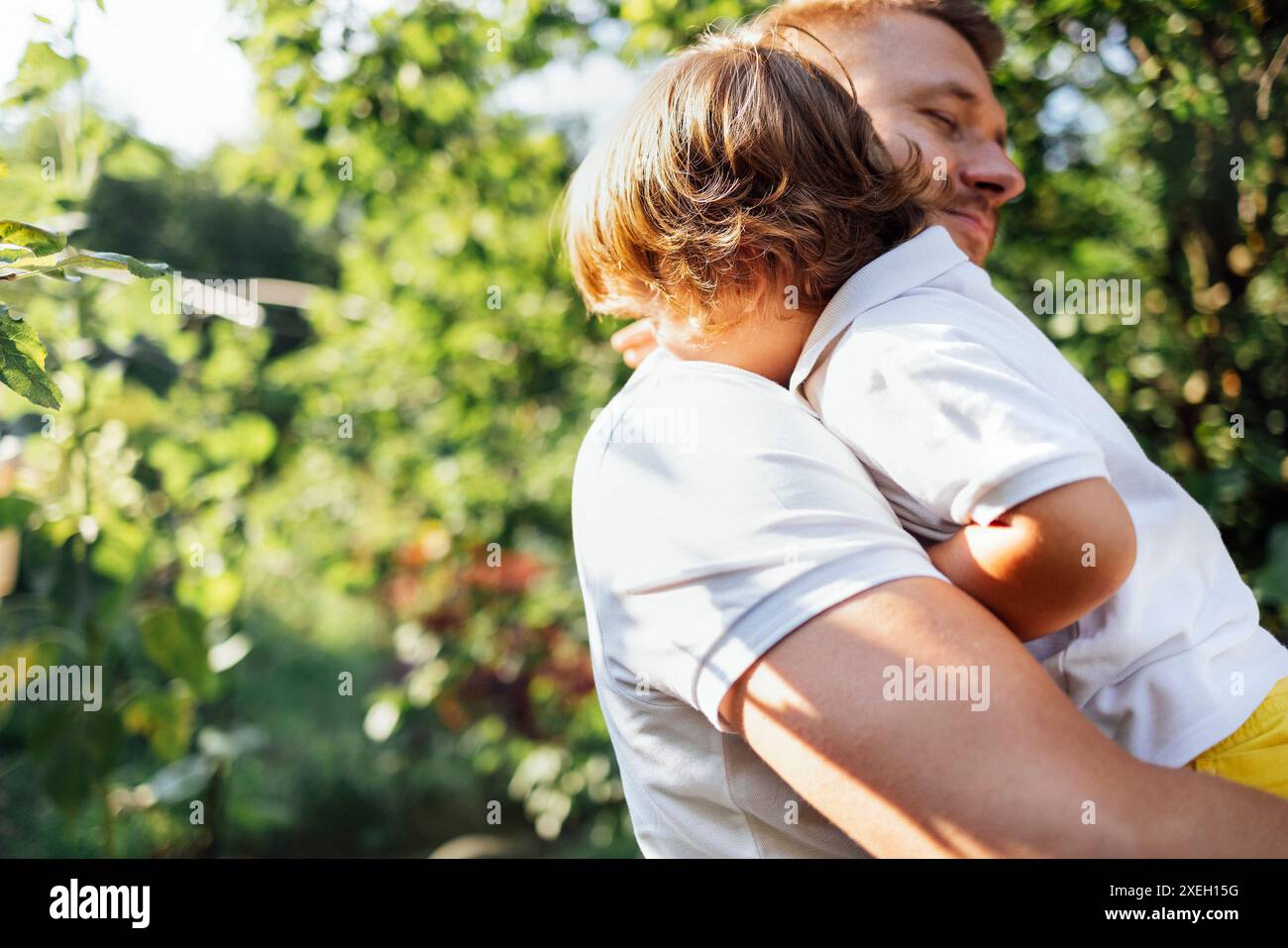 Felice padre che tiene in braccio il suo carino figlio in giardino Foto Stock