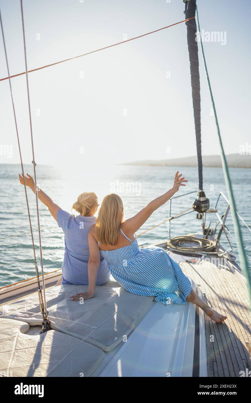 Due giovani donne caucasiche bionde incontrano l'alba sullo yacht. Foto Stock