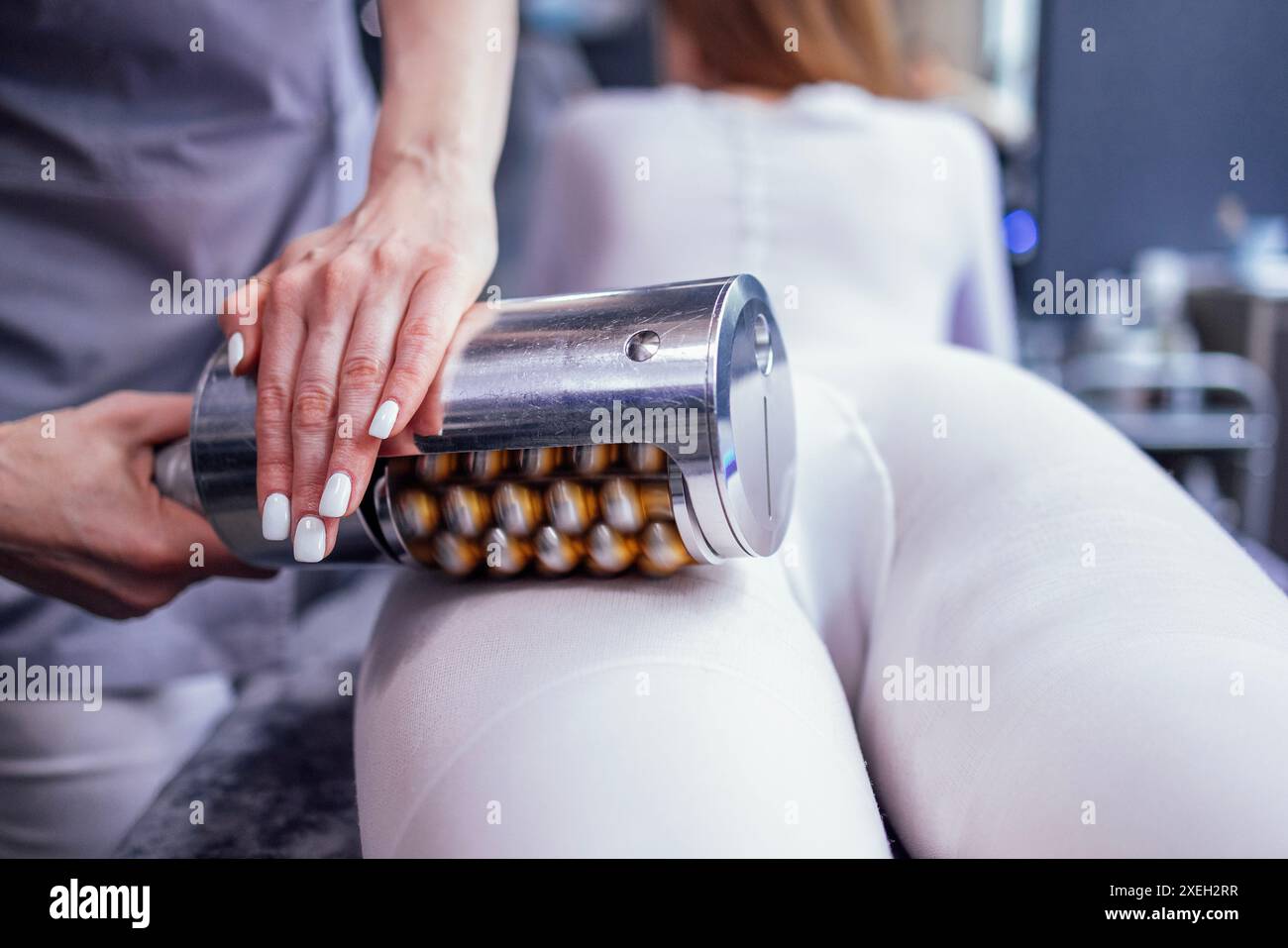 Estetista senza volto che usa il massaggiatore per rimuovere il grasso dai fianchi di cliente anonimo in salone Foto Stock