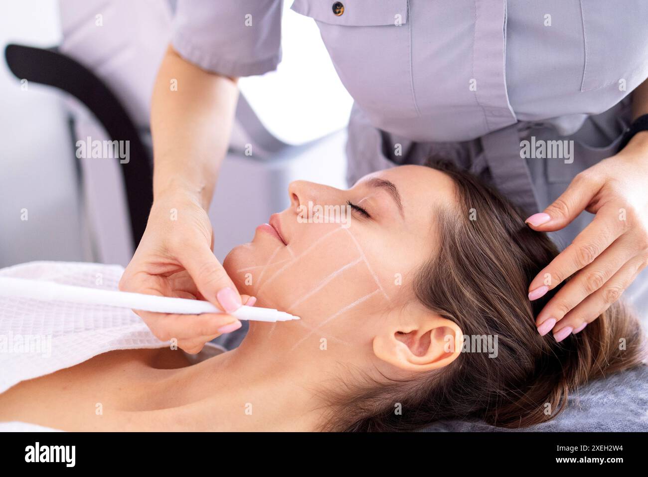 Medico che controlla la pelle della faccia della donna nella clinica di cosmetologia prima dell'ambulatorio di plastica Foto Stock
